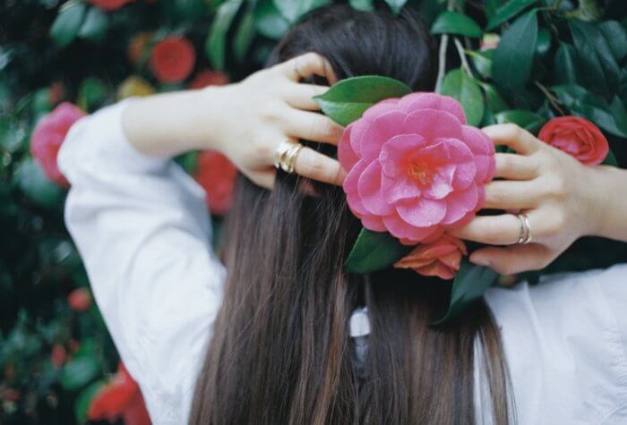 手で髪に花を添える女性の後ろ姿