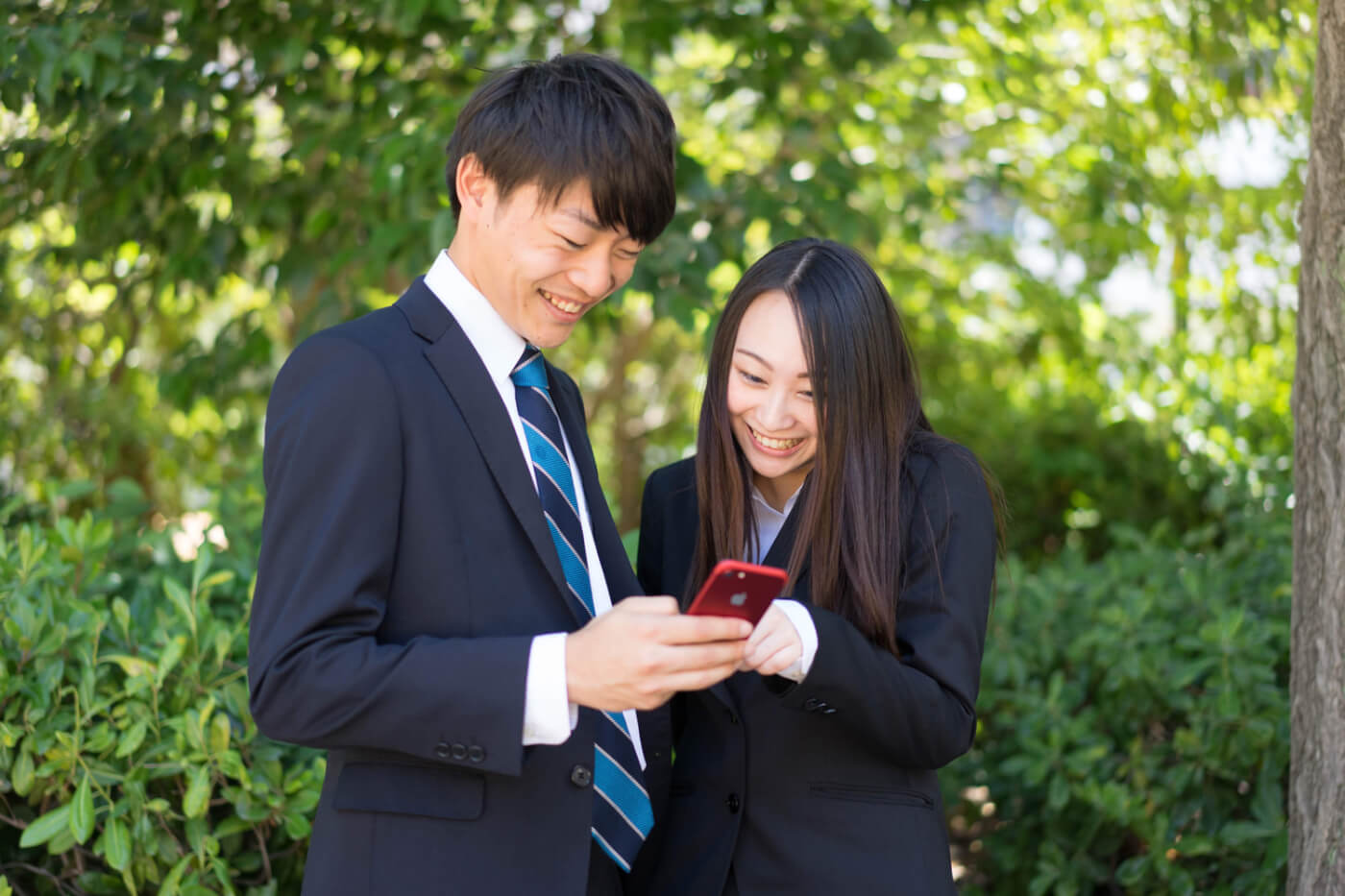 仕事中にスマホの画面を見て笑う男女