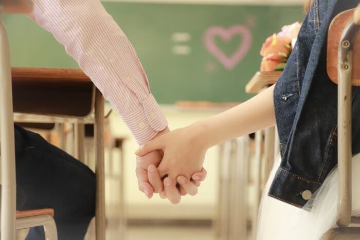 教室で手を握るカップル