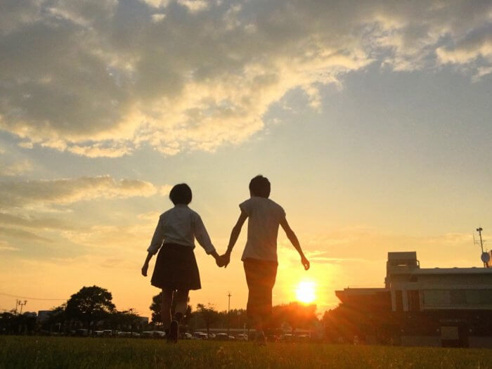 夕日に照らされる高校生カップル