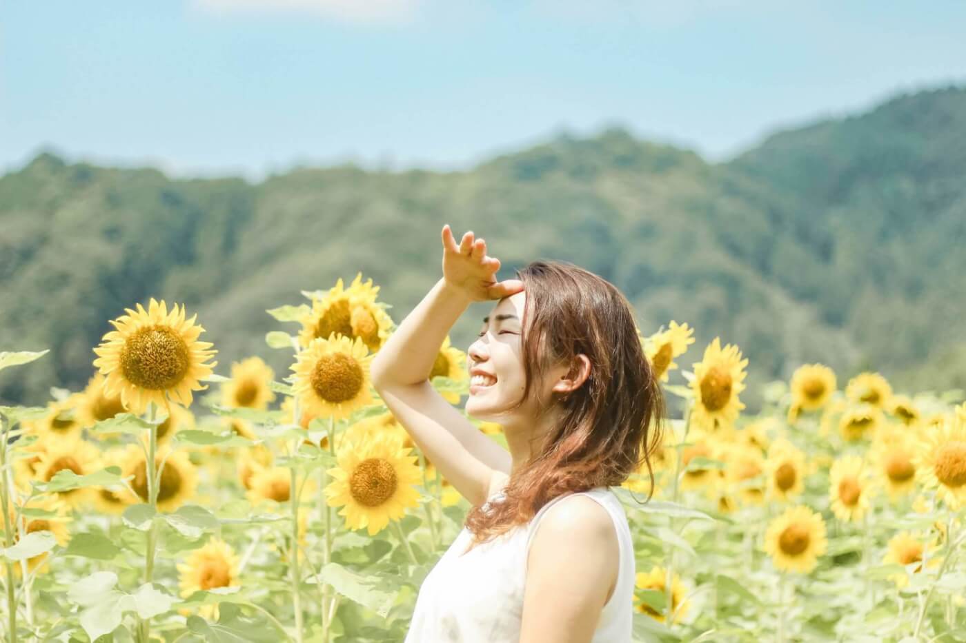 ひまわり畑の中で笑顔の女性